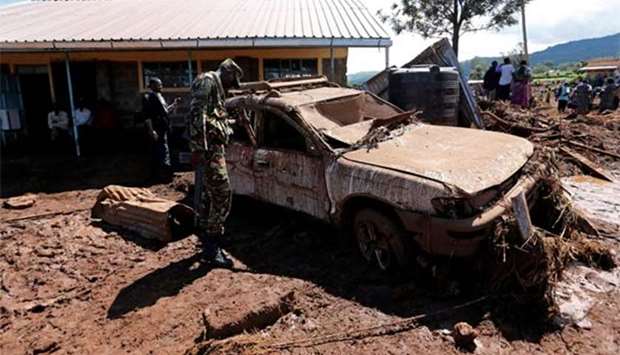 A military officer assesses a damaged car after a dam burst in Solio town near Nakuru, Kenya on Thursday.