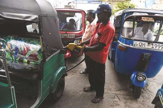 A Sri Lankan petrol pump attendant fills the tank of an auto rickshaw at a petrol station in Colombo.