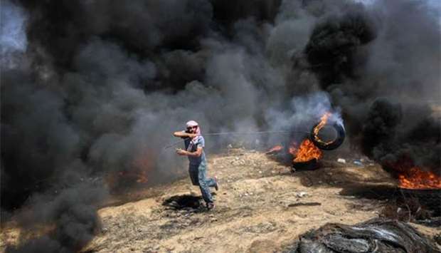 A demonstrator moves a burning tyre during clashes with Israeli forces along the border with the Gaza Strip, east of Khan Yunis. on Friday.