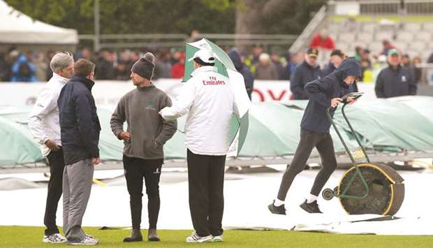 Umpires Nigel Llong (left) and Richard Illingworth check the pitch as groundsmen work on the wet pitch at Malahide cricket club on the first day of the Irelandu2019s debut Test against Pakistan in Dublin yesterday. (AFP)