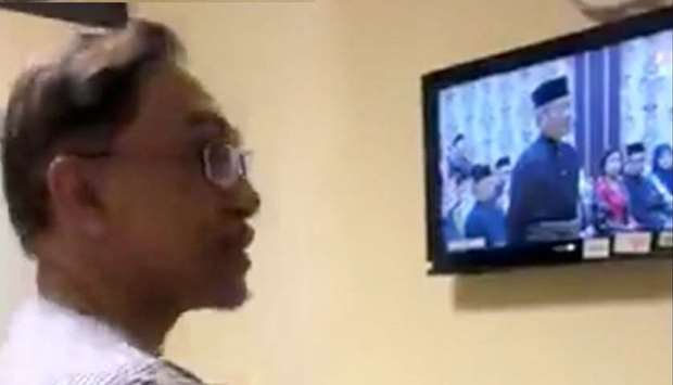 Malaysian political leader Anwar Ibrahim watches a live broadcast of the swearing in ceremony of newly-elected Malaysian Prime Minister Mahathir Mohamad
