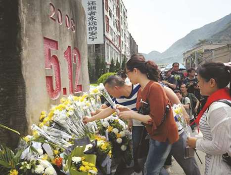 People place flowers at a memorial as they pay respects for victims of the 2008 Sichuan earthquake in Beichuan, in Chinau2019s southwestern Sichuan province, yesterday.