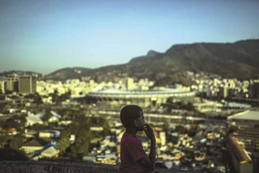 A child looks out from a rooftop in the Mangueira favela, as the Maracana Stadium stands in the background during the 2016 Olympics in Rio de Janeiro (file). MRV is not offering rooftop pools at its newest development, but it is making a high-end bet on Brazilu2019s low-income population.