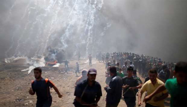 Palestinian demonstrators run from tear gas fired by Israeli troops during a protest