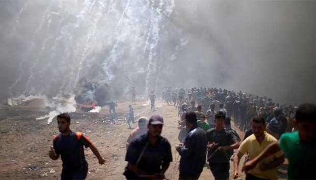 Palestinian demonstrators run from tear gas fired by Israeli troops during a protest