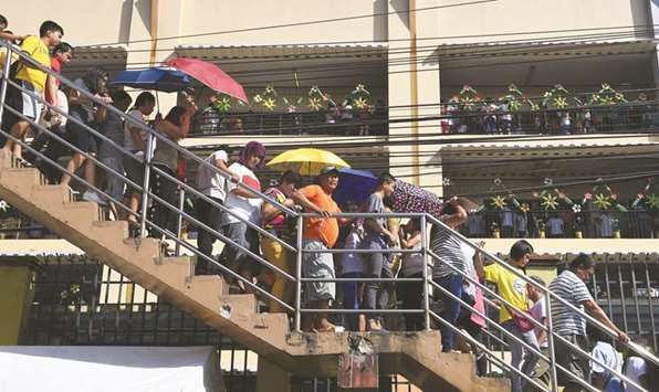 People cross a pedestrian bridge as they queue up to cast their ballots at a voting precinct in Quezon City, suburban Manila yesterday.