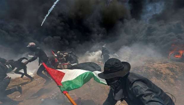 Palestinian demonstrators run for cover from Israeli fire and tear gas during a protest