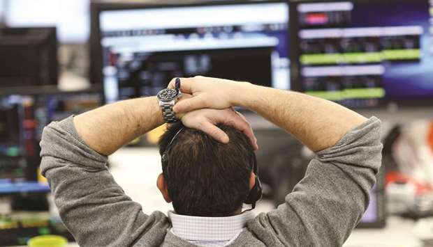A broker looks at financial information on computer screens on the IG Index trading floor in London (file). The FTSE 100 fell 0.2% yesterday to close at 7,710.98.