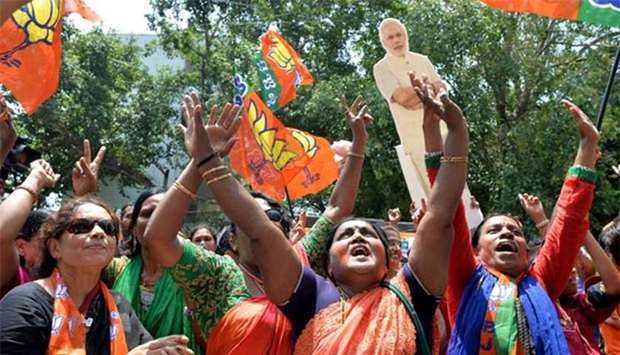 Supporters of India's Bhartiya Janata Party celebrate election results as they hold posters of Prime Minister Narendra Modi in front of the BJP state party office in Bengaluru on Tuesday.