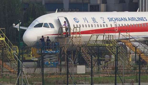 Workers inspect a Sichuan Airlines aircraft that made an emergency landing after a windshield on the cockpit broke off, at an airport in Chengdu, Sichuan province.