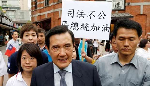 Members of the Kuomintang hold a placard as former Taiwanese president Ma Ying-jeou leaves from an event in Taipei on Tuesday.