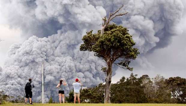 People watch as ash erupts from the Halemaumau crater during ongoing eruptions of the Kilauea Volcano in Hawaii.