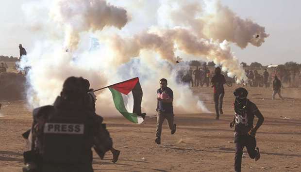 Palestinian demonstrators run from teargas fired by Israeli troops during a protest marking the 70th anniversary of Nakba, at the border in the southern Gaza Strip, yesterday.