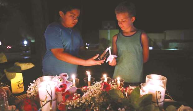 Two boys light candles during a vigil for the victims of a shooting at Santa Fe High School in Texas on Friday night.
