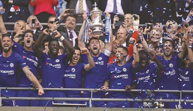 Chelseau2019s Gary Cahill lifts the FA Cup trophy as his teammates celebrate their win in the final against Manchester United at Wembley stadium in London yesterday. (AFP)