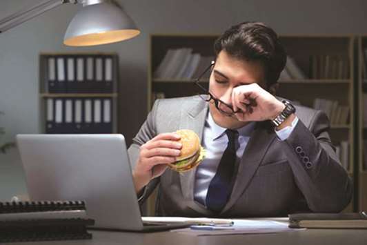 The businessman late at night eating a burger.