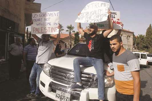 Palestinian men holding banners sit atop a car carrying members of a US delegation, believed to be from the US consulate in Jerusalem, near an event space in Beit Jala in the occupied West Bank, yesterday.