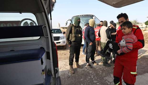 A member of the Syrian Arab Red Crescent carries a wounded child as civilians from the besieged Shiite areas of Fuaa and Kafraya in rebel-held northwestern Syria arrive in Aleppo's Al-Eis crossing yesterday.