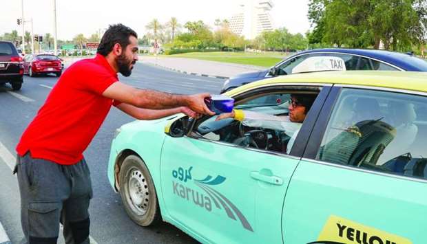 A taxi driver receiving an Iftar box from an Ooredoo volunteer.rnrn