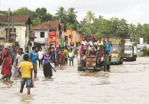 People walking through a flooded street in the suburb of Kaduwela in Colombo yesterday as monsoon rains lashed large parts of the island. Flood related accidents have killed at least eight people and damaged nearly 1,000 homes this week, according the Disaster Management Centre.
