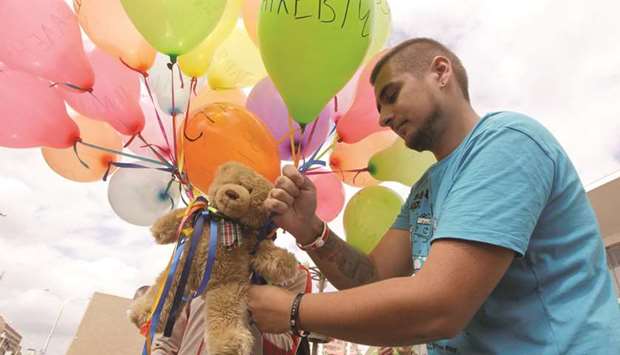 This picture taken on August 12, 2012 shows a man attaching a teddy bear to balloons during an opposition picket in central Minsk.