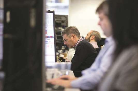 Traders study information on trading screens at ETX Capital in central London (file). The  FTSE 100 fell 1.1 % to close at 7,788.55 yesterday.