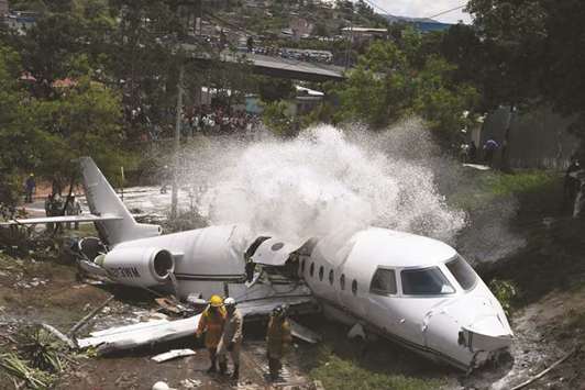 Firefighters spray foam on the wreckage of a plane after it went off the runway at Toncontin International airport and collapsed over a busy boulevard in Tegucigalpa on Tuesday.