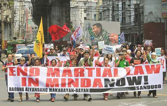 Activists display a banner and a mural of President Rodrigo Duterte to denounce the declaration of martial law in Mindanao island, one year after militants occupied parts of the southern city of Marawi during a protest outside the presidential palace in Metro Manila, yesterday.