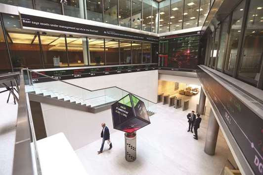 Visitors walk past an illuminated rotating cube displaying share price information in the atrium of the London Stock Exchange Groupu2019s offices in Paternoster Square. The London bourse ended yesterdayu2019s session 0.9% lower at 7,716.74 points.