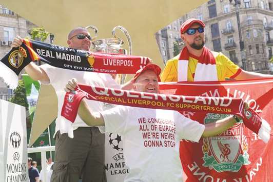 Liverpool fans pose in front of the UEFA Champions League trophy on display at the fan zone in Kiev yesterday. (AFP)