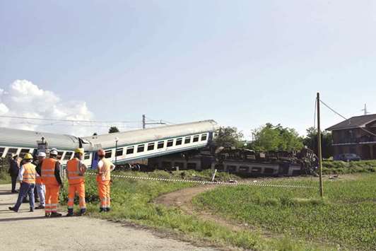 Police and railway technicians are seen near the site of the crash between a regional train and a rig truck that had stopped on the tracks in Caluso, outside Turin.