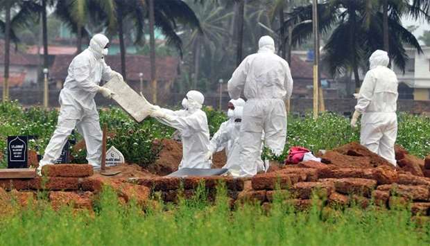 Doctors and relatives wearing protective gear dig a grave to bury the body of a victim, who lost his battle against the brain-damaging Nipah virus, during his funeral at a burial ground in Kozhikode