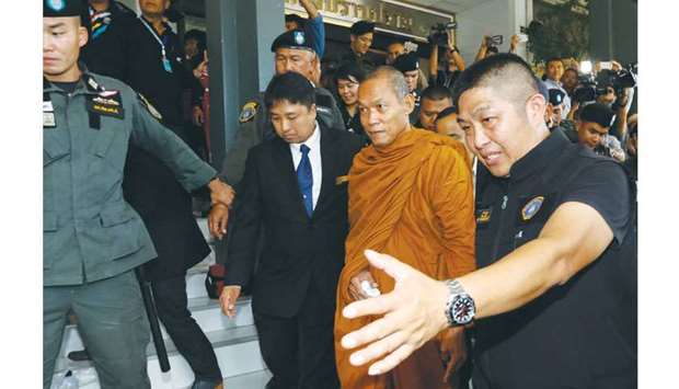 Luang Pu Buddha Issara, 62, an activist monk, is escorted by police officers at the Thai Police Crime Suppression Division headquarters in Bangkok yesterday.