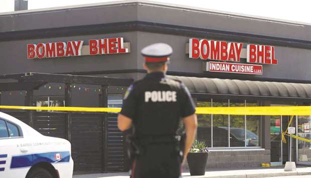 A police officer stands in front of the Bombay Bhel restaurant in Mississauga, Ontario, where two men set off a bomb late on Thursday night.
