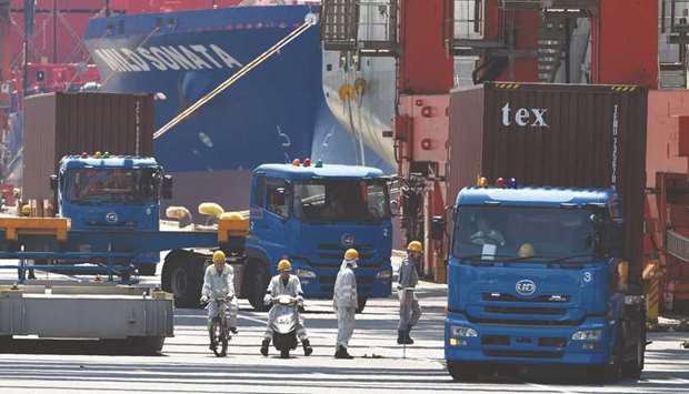 Trucks are seen transporting containers from a pier in Tokyou2019s port. Japanu2019s exports accelerated in April on increased shipments of cars and machines used to make semiconductors and they are seen likely to continue growing.