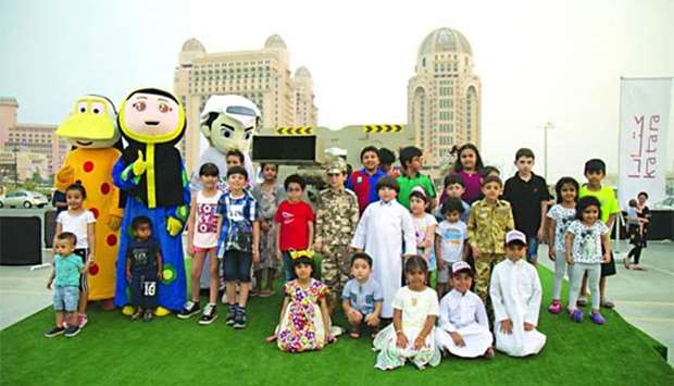 A group of children and mascots pose in front of the Ramadan cannon at Katara.