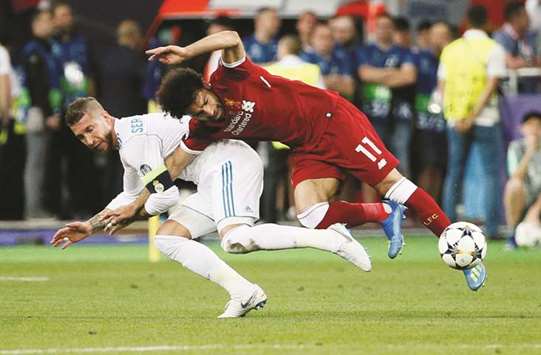 Liverpoolu2019s Mohamed Salah (right) falls in a challenge with Real Madridu2019s Sergio Ramos during their UEFA Champions League match in Kyiv on Saturday. (Reuters)