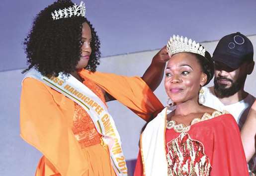The winner of the Miss Handicap Cameroon 2018 beauty pageant for disabled, Laura Tchokotcheu (left), who lost an arm in an accident with a corn grinder machine when she was 11, sets the crown of Getheme Lokou, winner of the Miss Handicap Ivory Coast 2018 beauty pageant for disabled in Abidjan during the beauty pageant aiming at changing mentalities on disability in Africa.