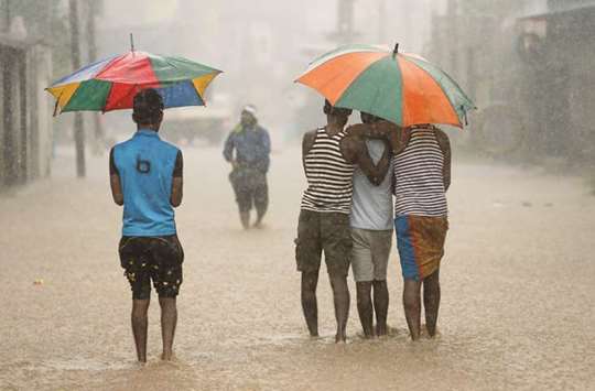 Men walk along a flooded road in the heavy rains in Malwana, near Colombo yesterday.