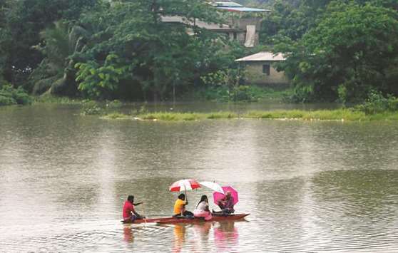 Villagers travel in a boat to cross the towns near a flooded road in Malwana, near Colombo, yesterday.