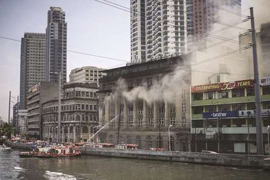 Firemen extinguish a fire at the administrative offices of the National Archives of the Philippines in Manila, yesterday.