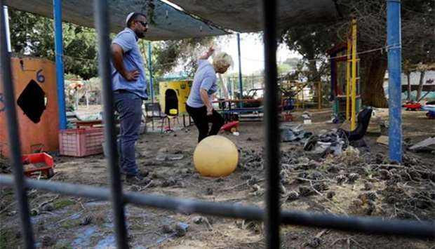 People stand in a kindergarten yard damaged by mortar shells, on the Israeli-Gaza border on Tuesday.