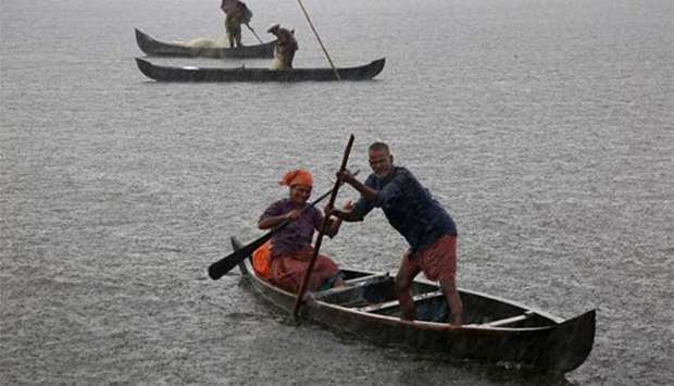 A fisherman and his wife row their boat in a fishing farm as it rains heavily on the outskirts of Kochi on Tuesday.