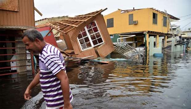 a man walks past destroyed homes in Catano, Puerto Rico