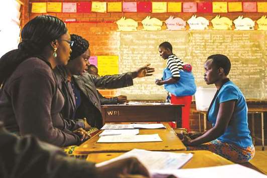 A prospective voter (left) checks her voter registration details with Zimbabwe Election Commission officials yesterday at an inspection centre in Harare.