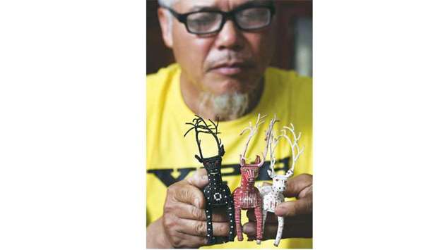 Nguyen Truong Chinh displaying intricately crafted animals made from plastic bags by his son and death row inmate Nguyen Van Chuong, during an interview with AFP at his home in Hanoi.