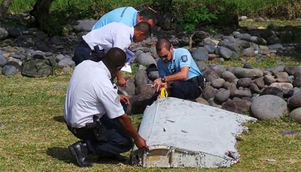 French gendarmes and police inspect a large piece of plane debris which was found on the beach in Saint-Andre, on the French Indian Ocean island of La Reunion, on July 29, 2015.