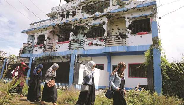 File photo shows residents who returned from evacuation centres walk past a bullet-ridden house believed to have been rented by pro-Islamic State militant leaders before their attack on the region, in Basak, Malutlut district in Marawi city.