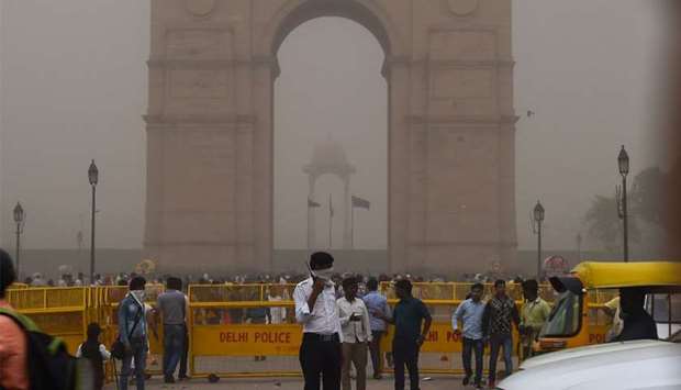 An Indian traffic policeman covering his face as he stands on duty during a dust storm in New Delhi