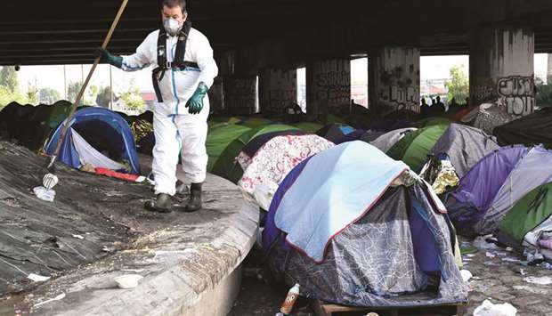 A worker cleans up the Millenaire migrant camp along the Canal de Saint-Denis near Porte de la Villette, northern Paris, following its evacuation yesterday.